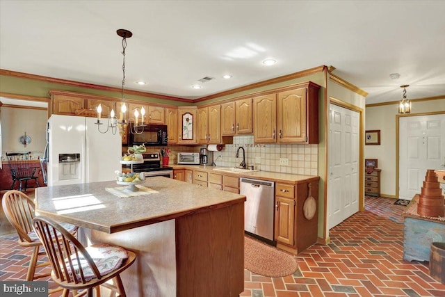 kitchen with a chandelier, a breakfast bar area, stainless steel appliances, brick floor, and a sink