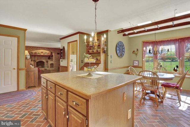kitchen featuring an inviting chandelier, a kitchen island, brick floor, and hanging light fixtures