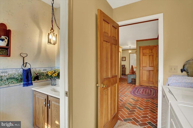 laundry room featuring separate washer and dryer, wallpapered walls, laundry area, and brick floor