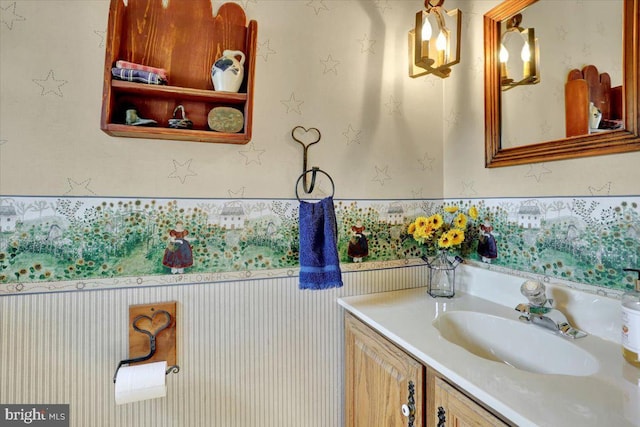 bathroom featuring wallpapered walls, a wainscoted wall, and vanity