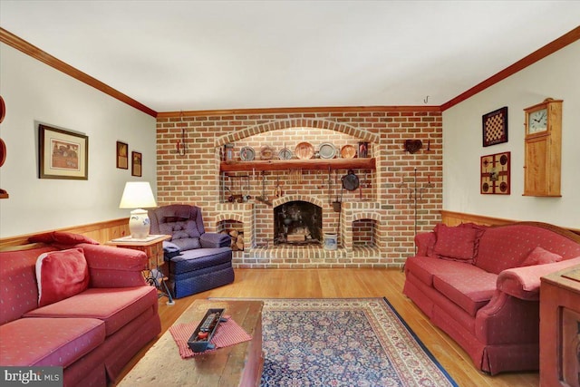 living room with a wainscoted wall, wood finished floors, a fireplace, and crown molding