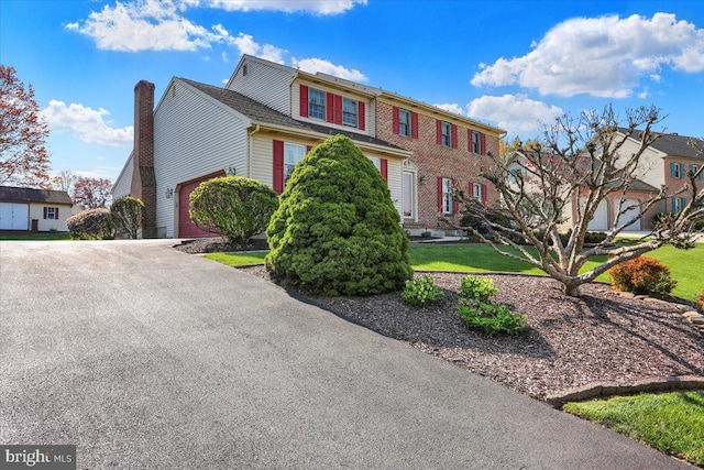 colonial house featuring a chimney, aphalt driveway, and a residential view