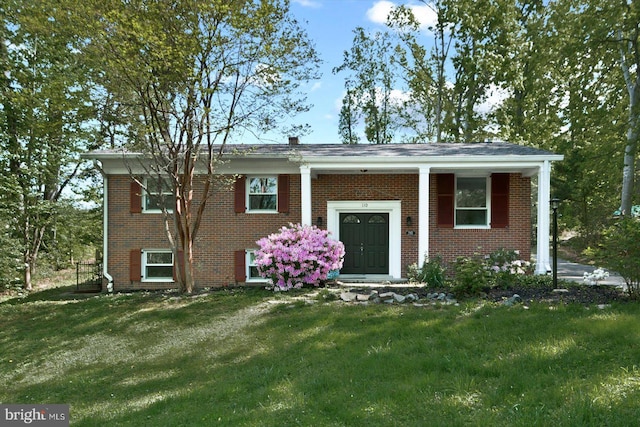 raised ranch with brick siding and a front yard