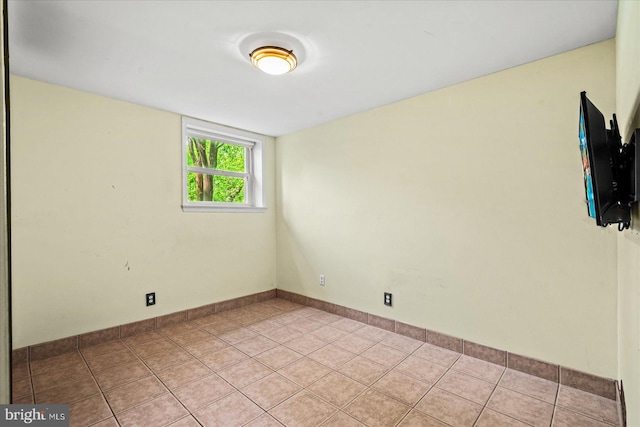 empty room featuring baseboards and light tile patterned floors