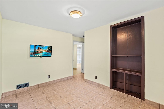 tiled empty room featuring baseboards and visible vents