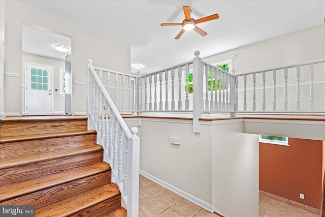 stairs featuring tile patterned floors, a ceiling fan, and baseboards
