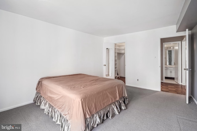 carpeted bedroom with a walk in closet and baseboards
