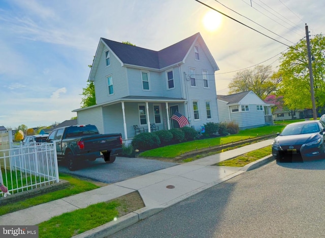 view of front facade featuring fence, covered porch, and a front yard