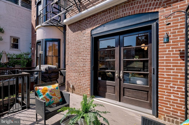 view of exterior entry featuring brick siding and french doors