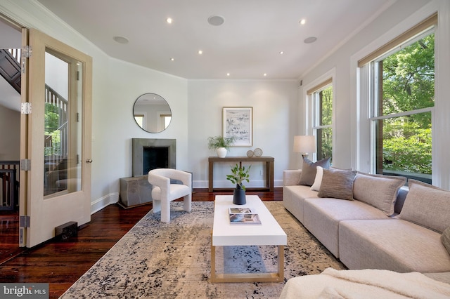 living area with baseboards, wood finished floors, recessed lighting, and ornamental molding