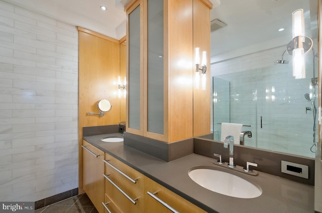bathroom featuring tile patterned floors, a sink, double vanity, and a stall shower