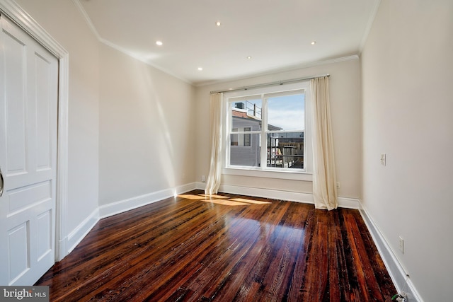 empty room with baseboards, crown molding, and wood finished floors