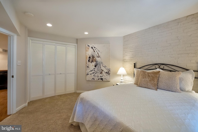 carpeted bedroom with recessed lighting, brick wall, baseboards, and a closet