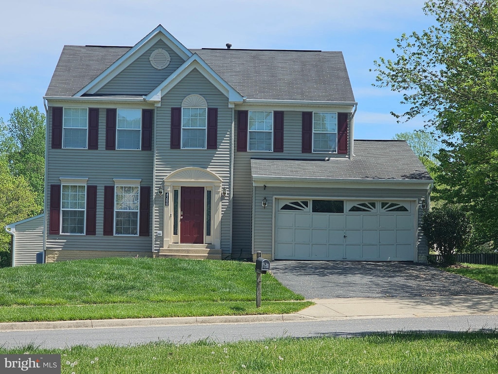 colonial house featuring aphalt driveway, a front yard, and roof with shingles