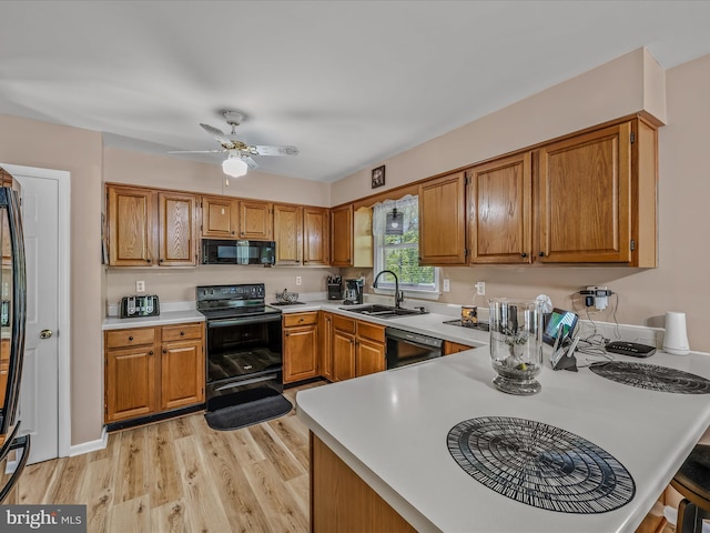 3322 Johnsons Mill Rd, Berkeley Springs, WV 25411 - kitchen featuring black appliances, a sink, light countertops, light wood-style floors, and brown cabinetry