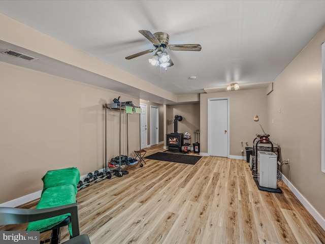 3322 Johnsons Mill Rd, Berkeley Springs, WV 25411 - workout room featuring a wood stove, wood finished floors, a ceiling fan, and baseboards