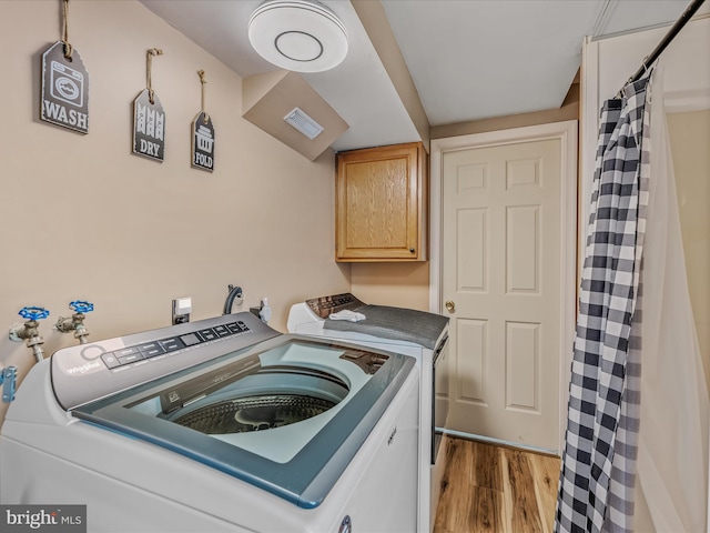 3322 Johnsons Mill Rd, Berkeley Springs, WV 25411 - washroom with washing machine and clothes dryer, wood finished floors, and cabinet space