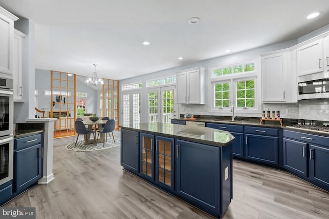 13017 English Turn Dr, Silver Spring, MD 20904 - kitchen with white cabinets, appliances with stainless steel finishes, a sink, blue cabinetry, and decorative backsplash