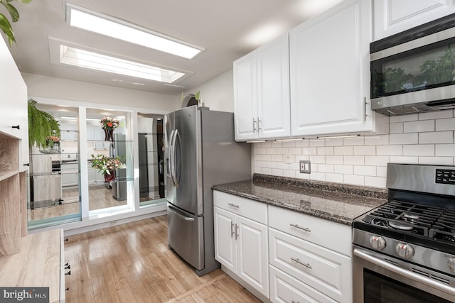 5511 Gwyn Pl, Alexandria, VA 22312 - kitchen with stainless steel appliances, white cabinetry, light wood-style floors, and decorative backsplash