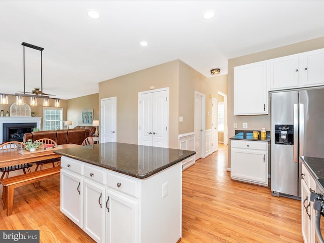 kitchen featuring stainless steel fridge with ice dispenser, a wainscoted wall, a center island, white cabinetry, and open floor plan