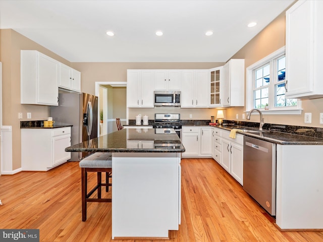 kitchen with a sink, light wood finished floors, a kitchen breakfast bar, a center island, and stainless steel appliances