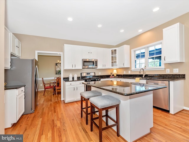 kitchen featuring white cabinets, appliances with stainless steel finishes, a breakfast bar, and light wood-type flooring