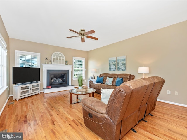 living room with light wood-style floors, baseboards, and ceiling fan