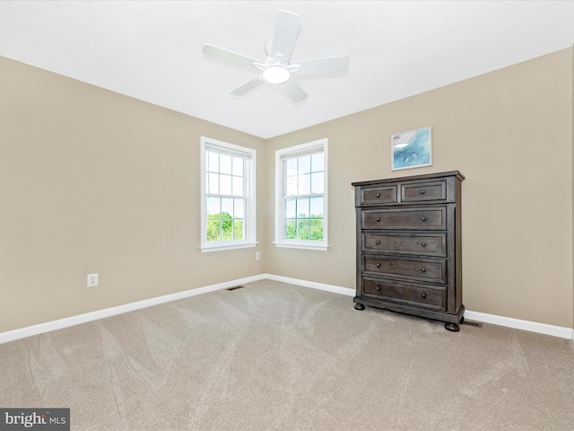 unfurnished bedroom with baseboards, visible vents, ceiling fan, and light colored carpet