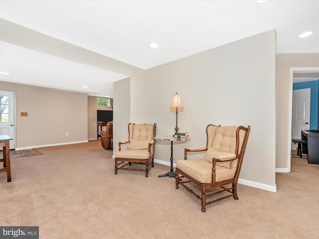 sitting room with baseboards and light carpet