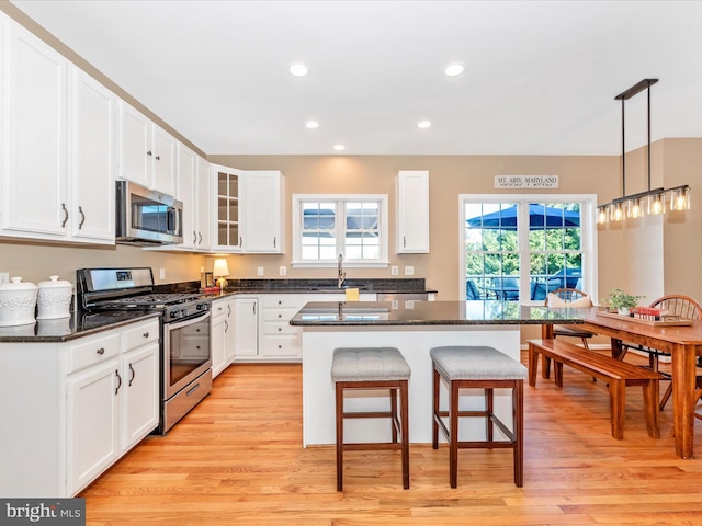 kitchen with a breakfast bar, light wood-style floors, a center island, a sink, and appliances with stainless steel finishes