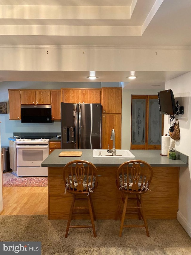 kitchen featuring brown cabinets, white electric range oven, black microwave, a sink, and stainless steel refrigerator with ice dispenser