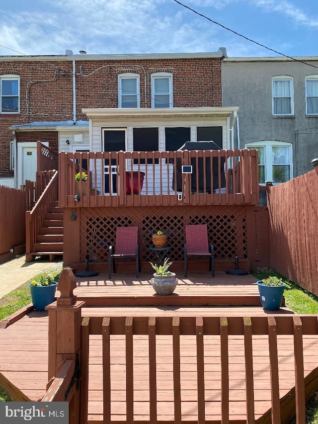 rear view of house featuring fence, stairway, and a deck