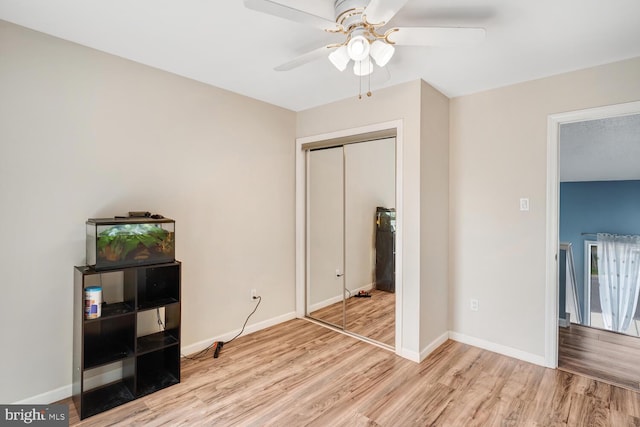 unfurnished bedroom with baseboards, a ceiling fan, light wood-style floors, and a closet