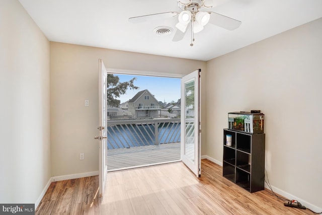 interior space featuring baseboards, visible vents, wood finished floors, and ceiling fan