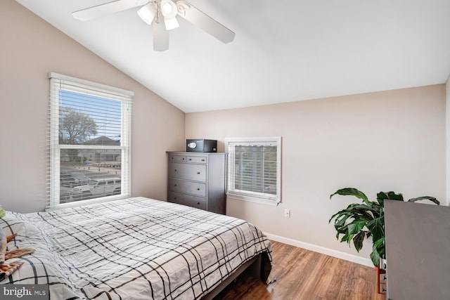bedroom with wood finished floors, a ceiling fan, vaulted ceiling, and baseboards