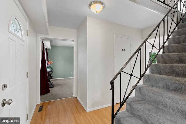 stairs featuring visible vents, wood finished floors, and baseboards
