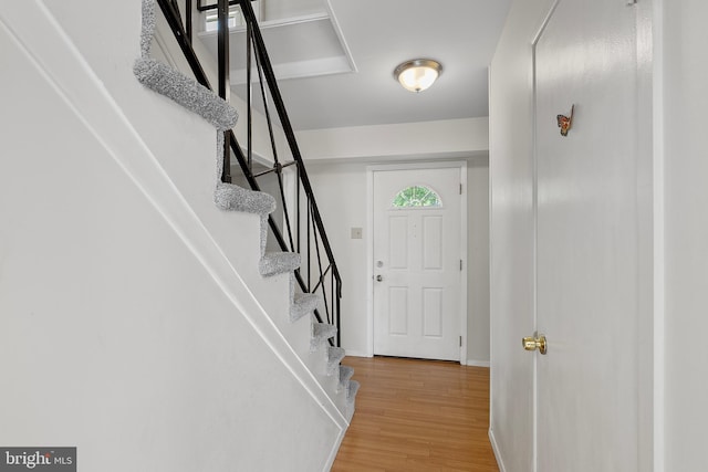 foyer entrance featuring baseboards, light wood-style floors, and stairway