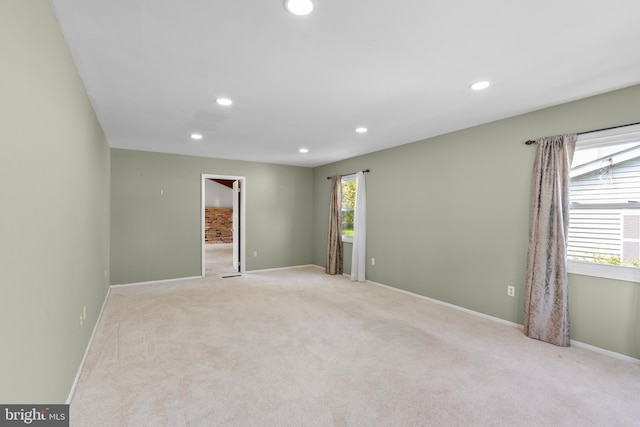 spare room featuring light colored carpet, baseboards, plenty of natural light, and recessed lighting