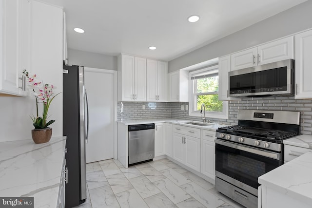 kitchen with white cabinetry, stainless steel appliances, marble finish floor, and a sink