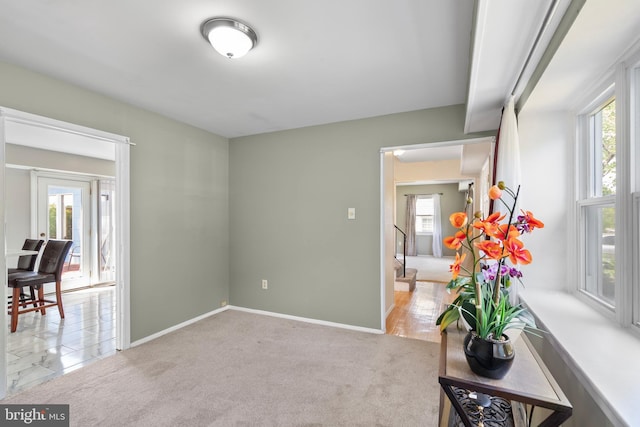 interior space with light colored carpet, baseboards, and plenty of natural light