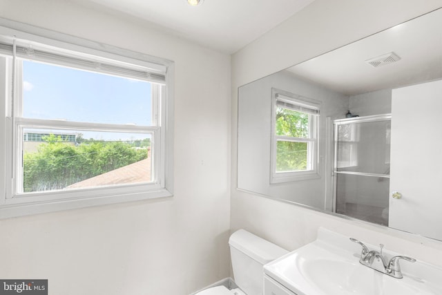 bathroom featuring a shower with door, toilet, visible vents, and vanity