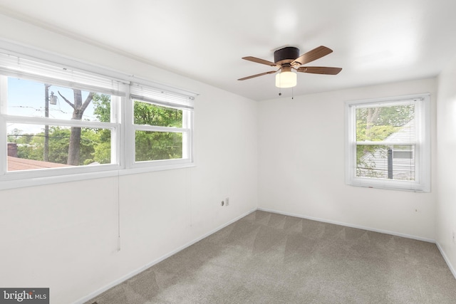 carpeted spare room with baseboards and a ceiling fan