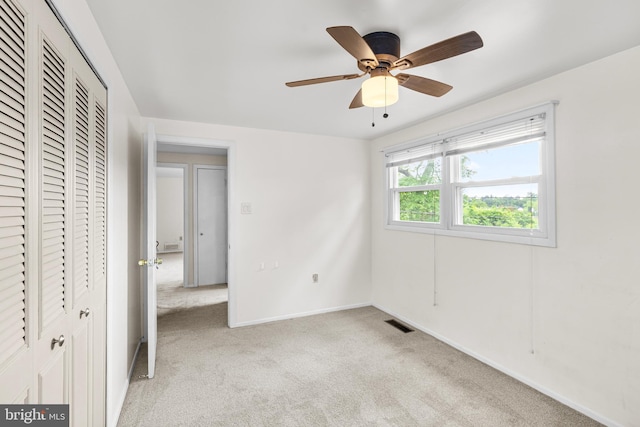 unfurnished bedroom with a closet, light colored carpet, visible vents, a ceiling fan, and baseboards