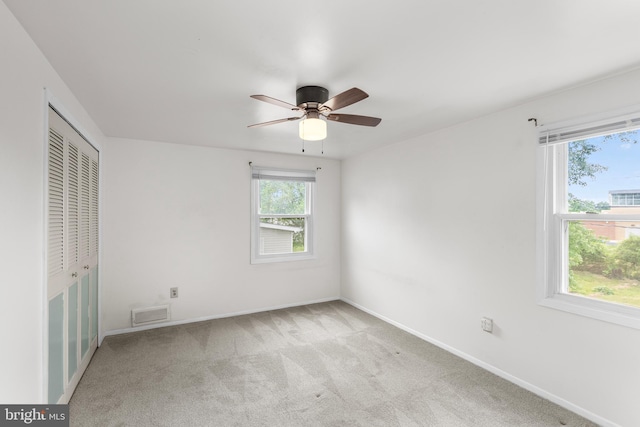 unfurnished bedroom featuring light colored carpet, ceiling fan, baseboards, and a closet