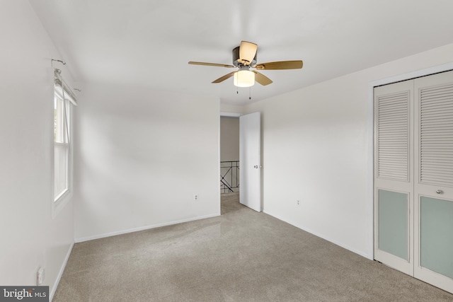 unfurnished bedroom featuring baseboards, a closet, ceiling fan, and carpet