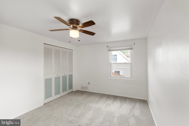 unfurnished bedroom with carpet, a closet, baseboards, and ceiling fan