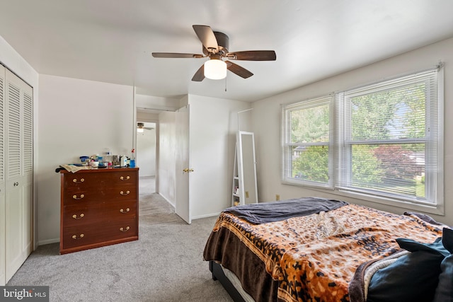 bedroom featuring a closet, light carpet, baseboards, and a ceiling fan