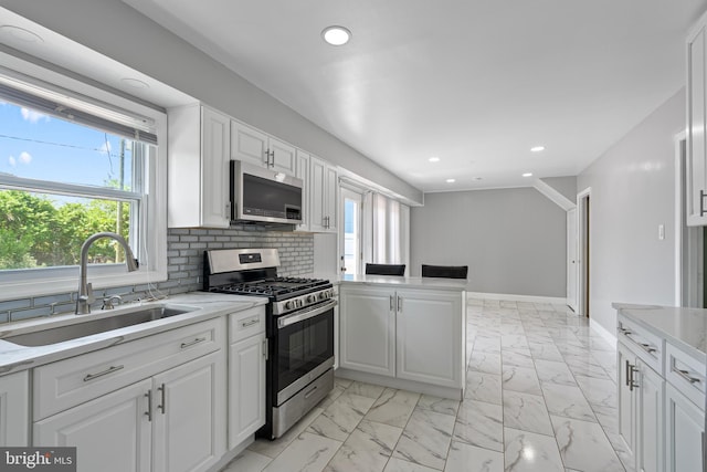 kitchen featuring a sink, white cabinetry, tasteful backsplash, appliances with stainless steel finishes, and marble finish floor
