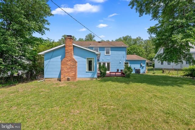rear view of house with a yard, a chimney, central AC unit, and fence