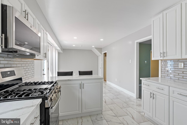 kitchen featuring stainless steel appliances, marble finish floor, light stone counters, white cabinetry, and backsplash